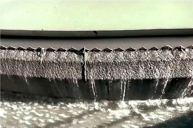water dripping out of metal gap in to river